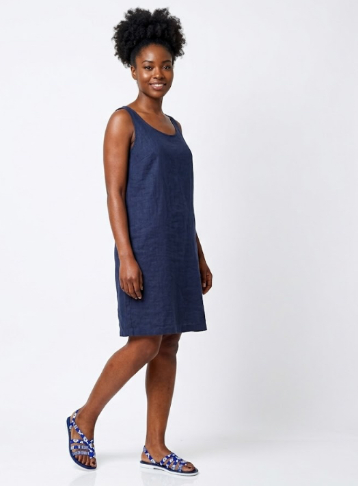 wardrobe with these stylish and comfortable flat sandals, as seen on a model in a sophisticated home setting. Featuring unique blue and white patterned straps and a natural tan sole, they are the perfect blend of casual elegance.  Ideal for pairing with everything from dresses to shorts for a chic summer look.